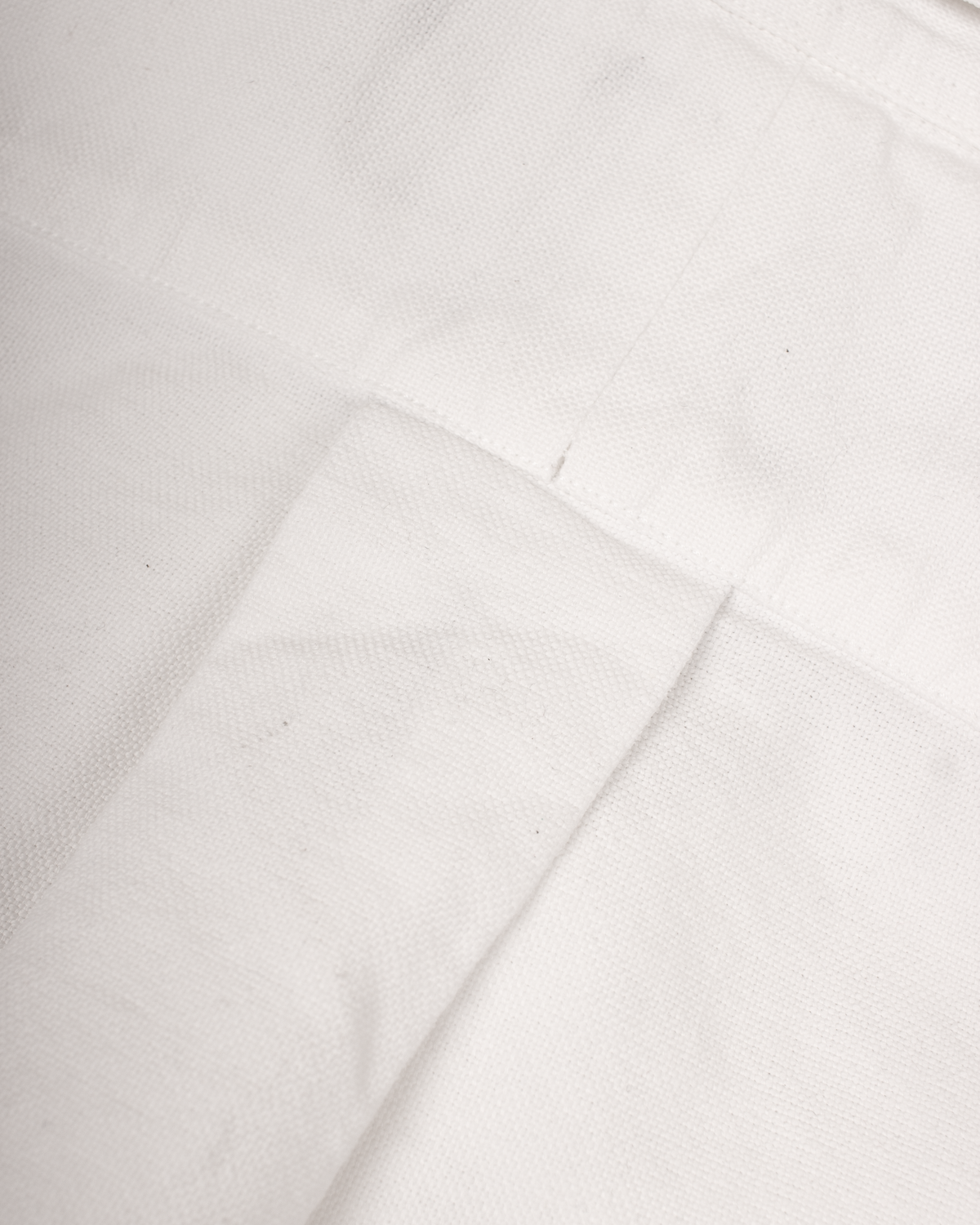 A close-up of white fabric with visible weave texture and a folded seam.