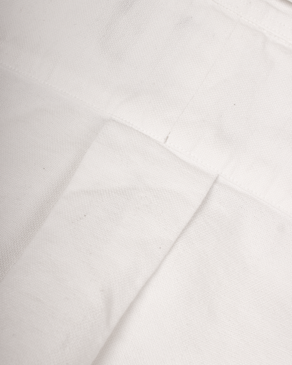 A close-up of white fabric with visible weave texture and a folded seam.