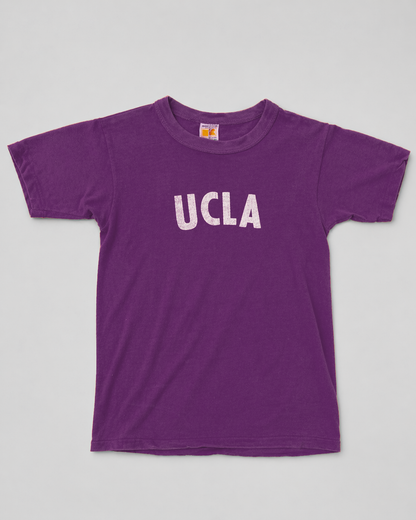 Purple t-shirt with 'UCLA' printed on it against a gray background single stitch I Love NY I love new york college tee harvard university highschool printed t-shirt 1970s 70s baby tee crop t-shirt vintage cropped tee 